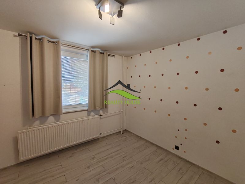 Ein Zimmer in einer 3-Zimmer-Wohnung mit einem Holzboden und einer gepunkteten Tapete.