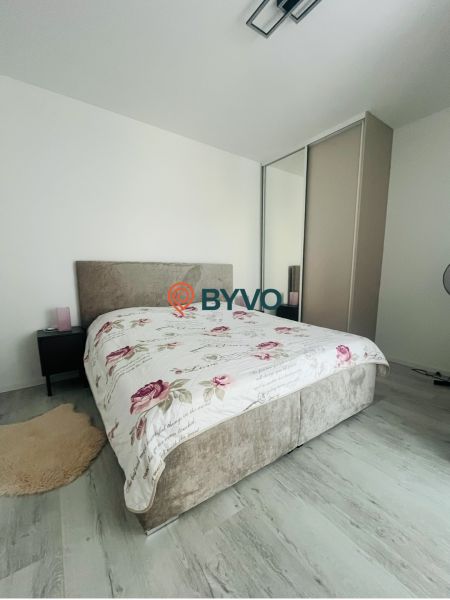 Schlafzimmer in einer 2-Zimmer-Wohnung mit Bett und Schrank, helle Wände, Boden mit Holzdekor.