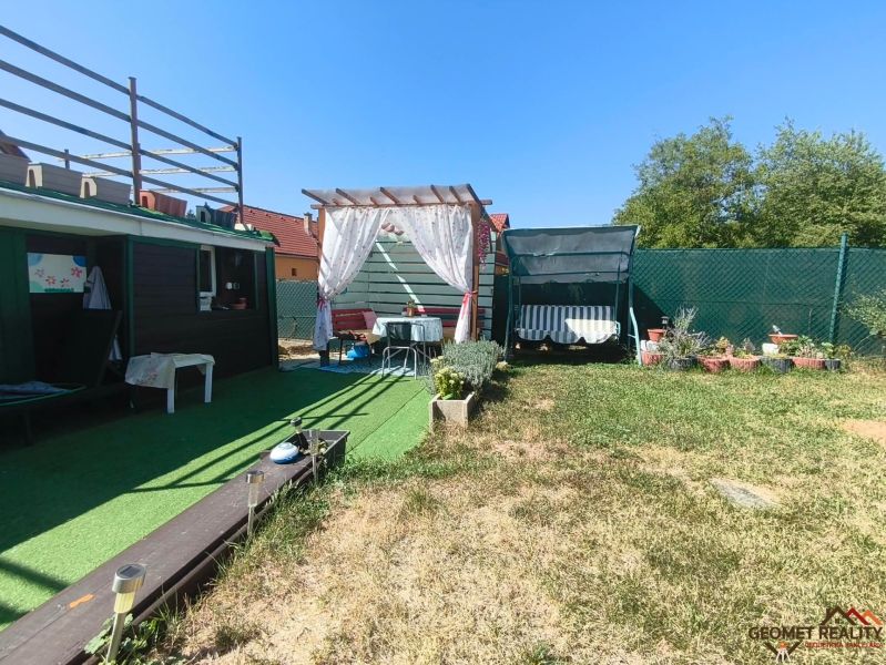 Der Garten des Einfamilienhauses in Divín mit Pavillon, Schaukel und grünem Rasen.