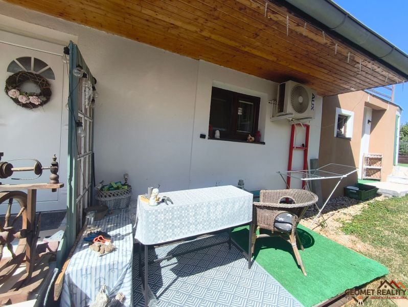 Die Terrasse des Einfamilienhauses in Divín mit Baldachin, Tisch und Rattansessel.