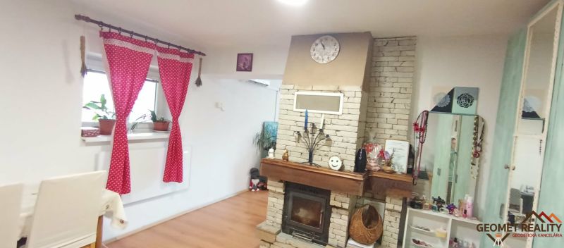Wohnzimmer in einem Einfamilienhaus mit Kamin und dekorativen Möbeln, Boden mit Holzdekor.