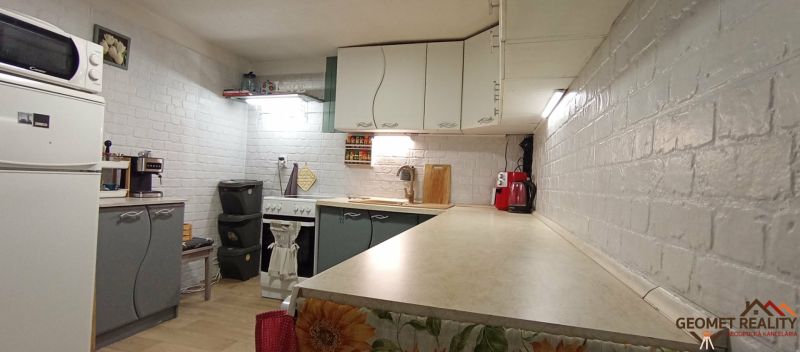 Küche in einem Einfamilienhaus mit weißen Ziegelwänden und Küchengeräten.