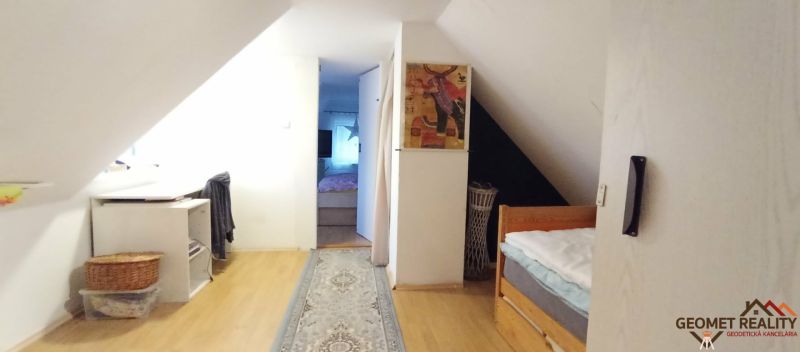 Der Dachbodenflur in einem Einfamilienhaus mit einem Boden in Holzoptik und einem Teppich.
