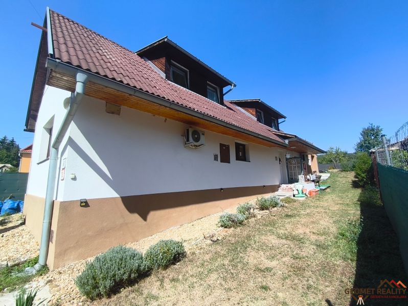 Ein Einfamilienhaus in Divín mit einem braunen Dach und einem Garten, umgeben von Rasen und Sträuchern.