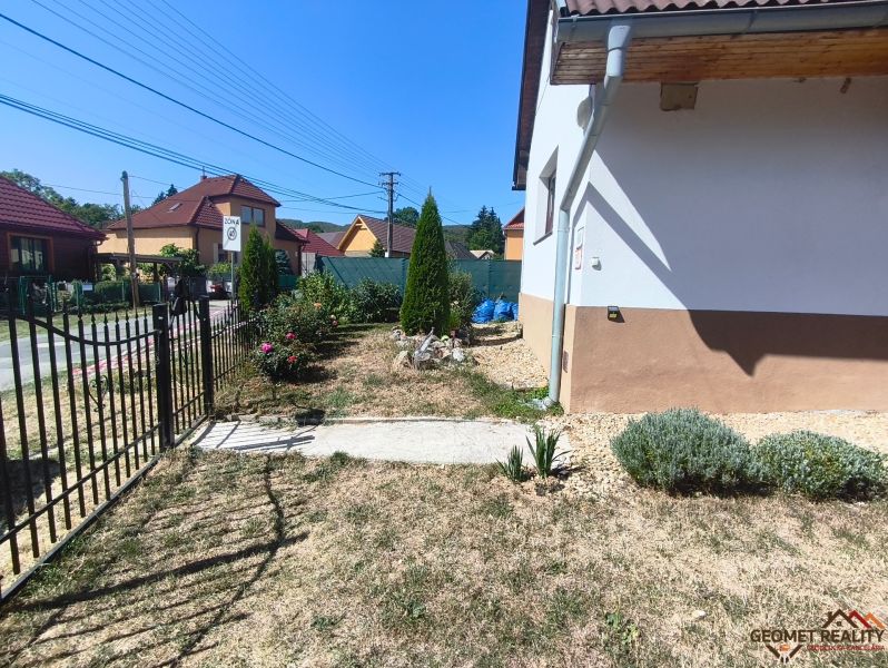 Ein Garten beim Einfamilienhaus in Divín mit Pflanzen und Rasen, umgeben von einem Zaun.