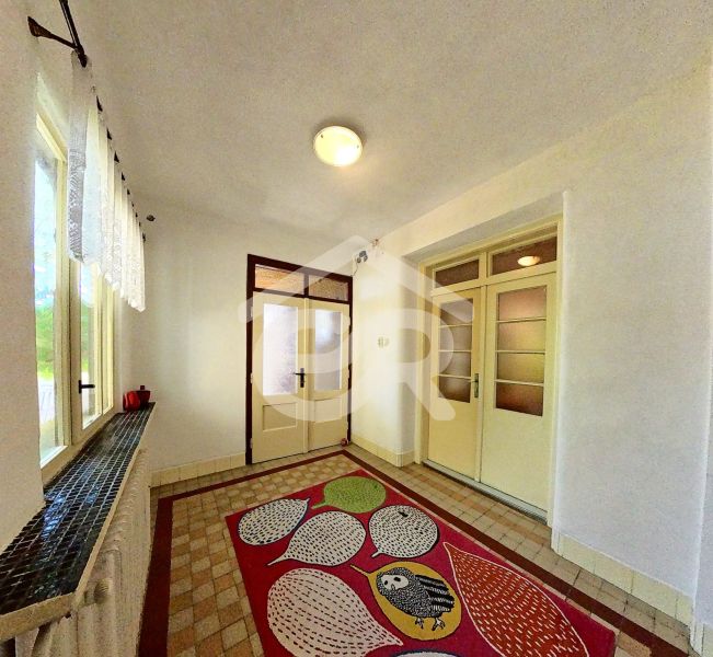 Der Flur in einem Einfamilienhaus mit einem bunten Teppich und Glastüren.