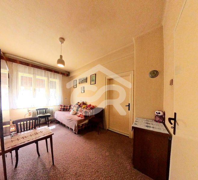 Ein Zimmer in einem Einfamilienhaus mit Teppichboden, einem Bett, Möbeln und Spielzeug auf dem Bett.