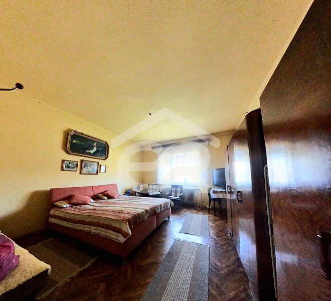 Schlafzimmer in einem Einfamilienhaus mit Holzboden, Bett, Schränken, Bilder an der Wand.