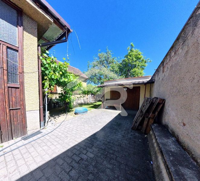 Höfe der Einfamilienhäuser in der Sládkovičova-Straße in Zlaté Moravce, umgeben von Grünflächen und mit Pflastersteinen ausgelegt.