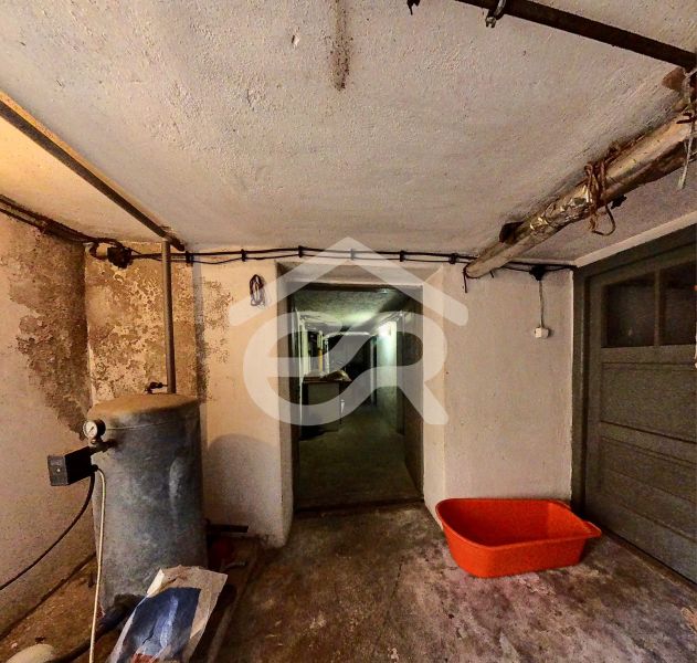 Der Keller eines Einfamilienhauses mit einem Tank und einem orangefarbenen Plastikbehälter auf dem Boden.