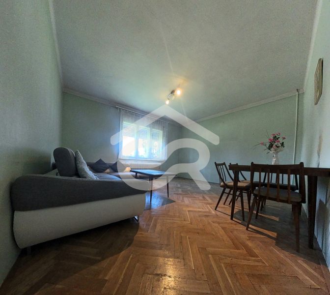Wohnzimmer in einem Einfamilienhaus mit Sofa, Tisch und Holzboden.