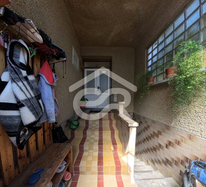 Eingangsbereich eines Einfamilienhauses mit Jacken und Topfpflanzen.