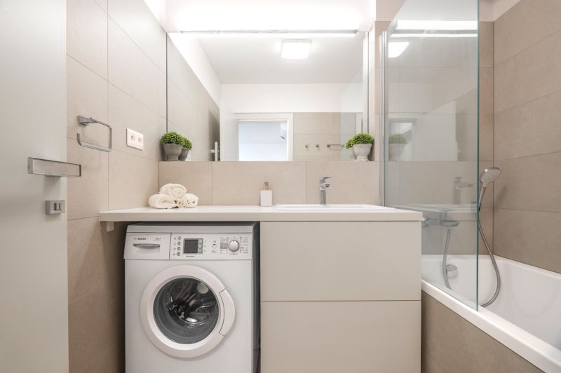 Badezimmer mit Dusche, Waschmaschine und Waschbecken in einer 2-Zimmer-Wohnung.