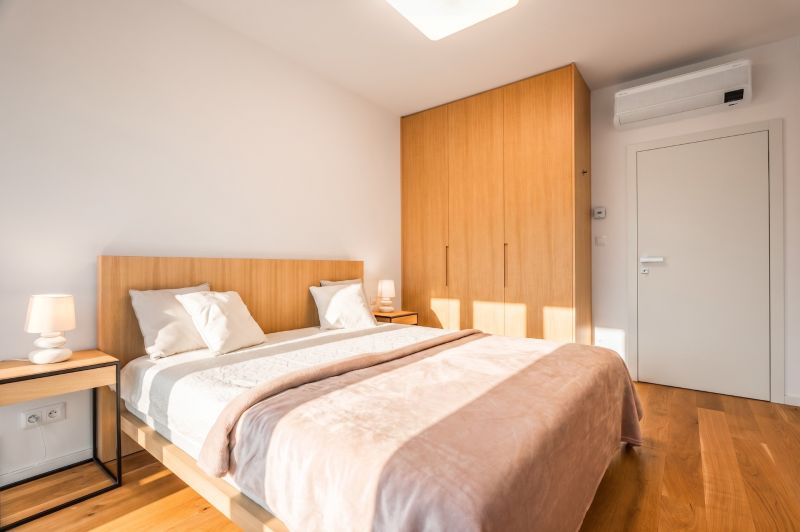Schlafzimmer mit Doppelbett, Kleiderschrank und Holzboden in einer 2-Zimmer-Wohnung.