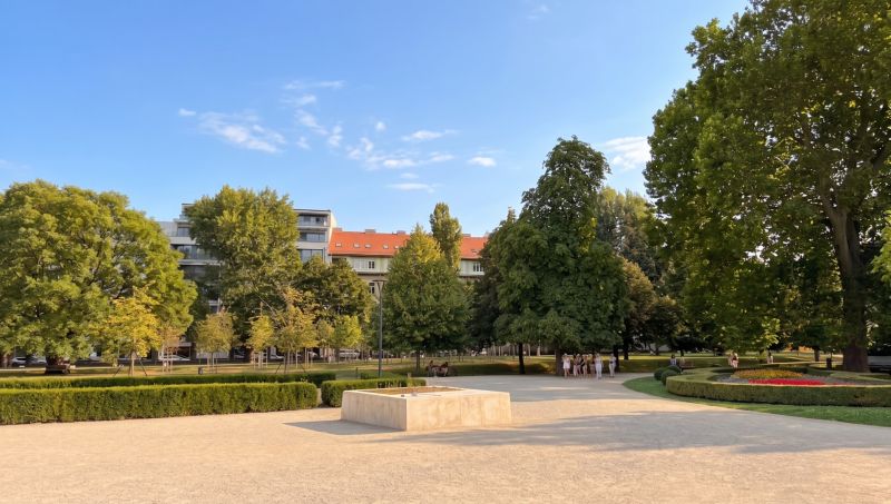Ein Garten mit bunten Blumen, Bäumen und Gebäuden in Bratislava - Altstadt auf der Banskobystrická.