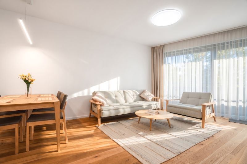Helles Wohnzimmer mit Holzboden, Sofa und Esstisch.