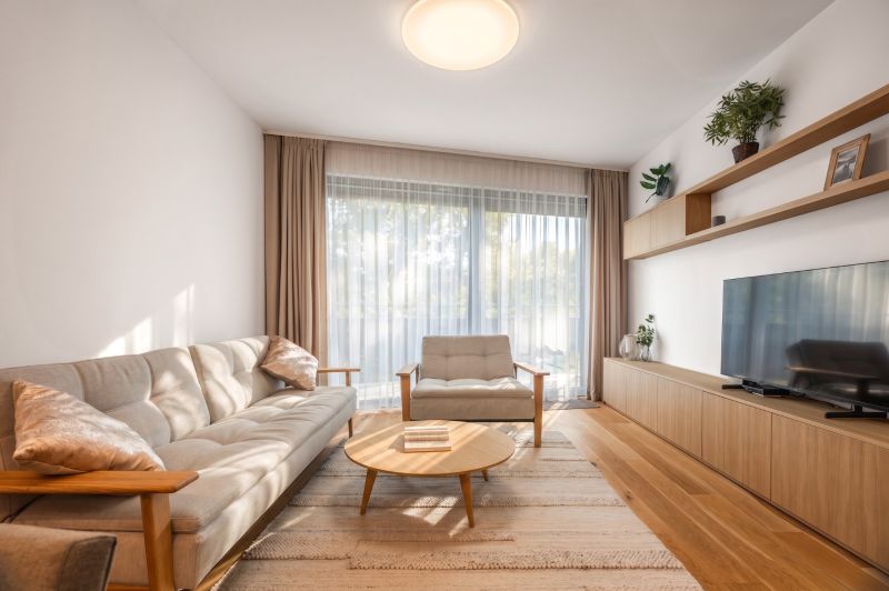 Wohnzimmer in einer 2-Zimmer-Wohnung, helle Möbel, ästhetischer Teppich, Boden mit Holzdekor.