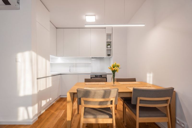 Küche in einer 2-Zimmer-Wohnung mit Esstisch und Boden in Holzoptik.