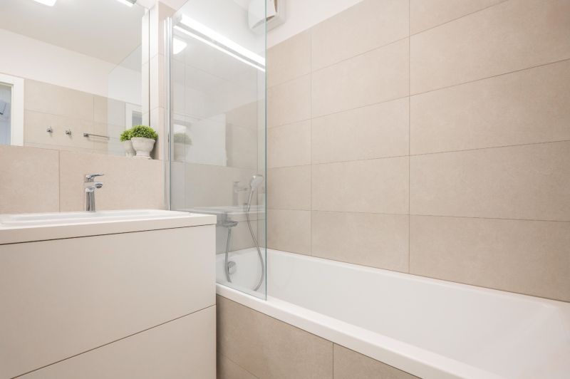 Badezimmer mit Badewanne und Waschbecken in einer 2-Zimmer-Wohnung, helle Fliesen.