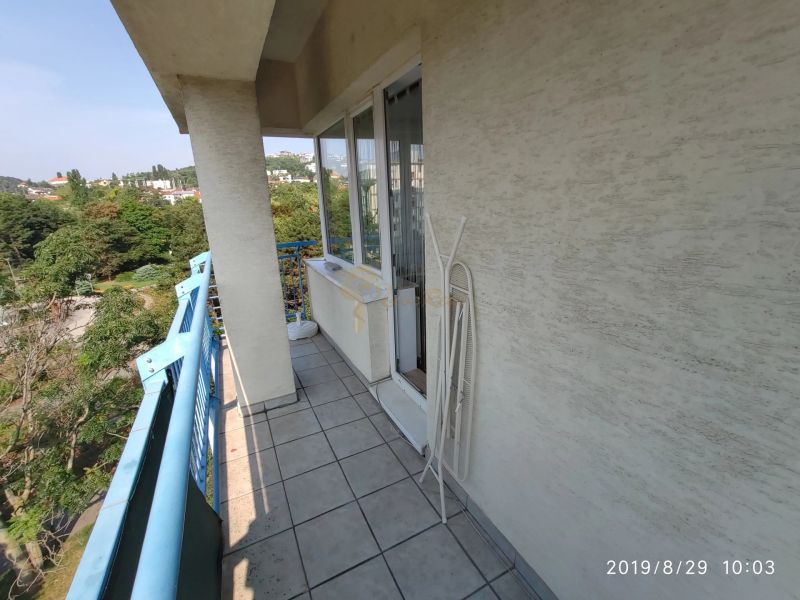 Balkon einer 2-Zimmer-Wohnung mit blauem Geländer und Blick ins Grüne in Bratislava.