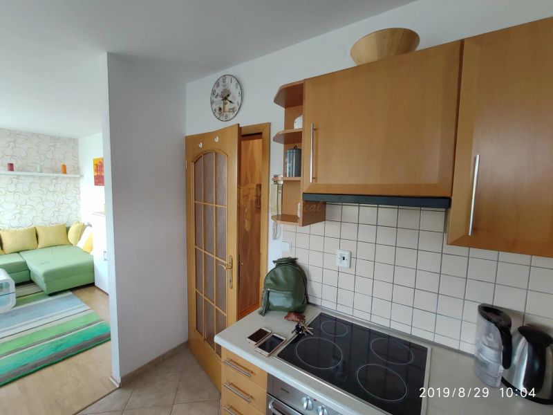 Küche in einer 2-Zimmer-Wohnung mit Holzschränken und Blick auf das Wohnzimmer.