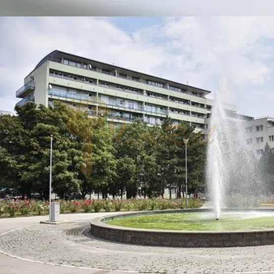 Der Brunnen auf dem Račianske mýto in Bratislava - Nové Mesto mit einem Wohnhaus im Hintergrund.