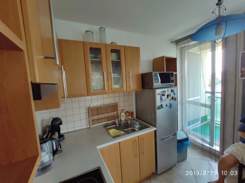 Küche mit Holzschränken, Mikrowelle und Kühlschrank in einer 2-Zimmer-Wohnung.