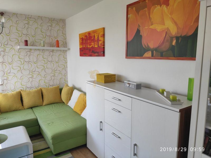 Wohnzimmer mit Sofa, Holzboden, dekorative Bilder und Kerzen.
