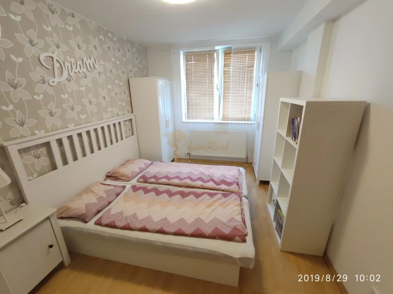 Schlafzimmer mit Bett, Holzboden und Blumenklebeband in einer Zweizimmerwohnung.