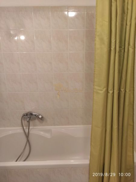 Badezimmer mit weißen Fliesen und einer Badewanne mit Vorhang in einer Zweizimmerwohnung.