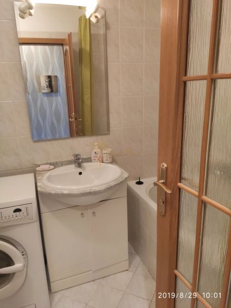 Badezimmer mit Waschbecken, Spiegel, Waschmaschine und Badewanne in einer 2-Zimmer-Wohnung.