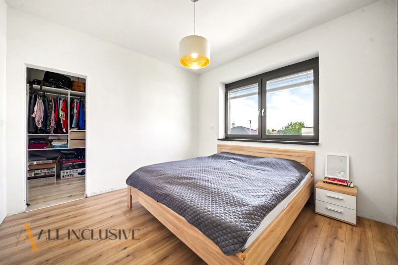 Schlafzimmer in einem Einfamilienhaus mit großem Bett, Schrank und Boden mit Holzdekor.