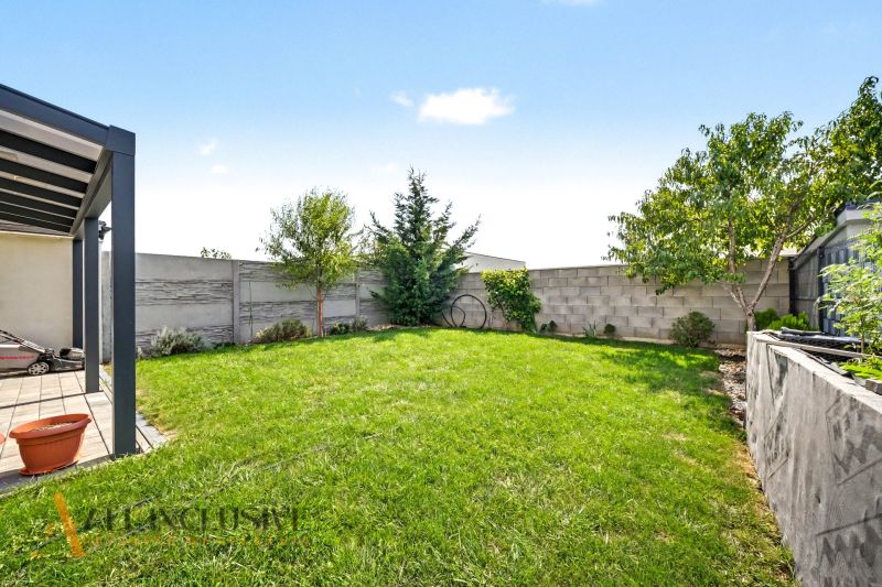 Garten eines Einfamilienhauses in Hrubá Borša mit Rasen, Bäumen und Terrasse.