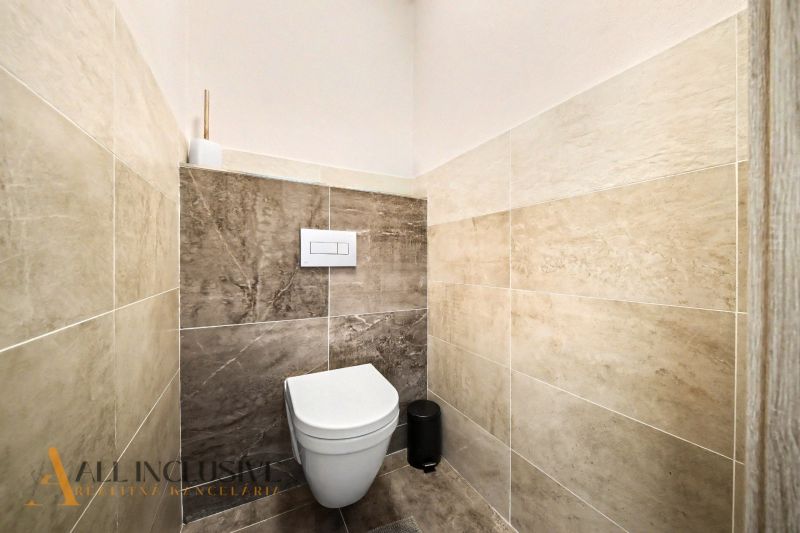 Toilette im Einfamilienhaus mit Fliesen in natürlichen Farbtönen.