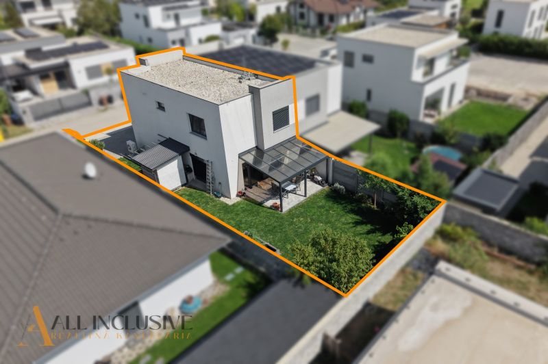 Ein Einfamilienhaus in Hrubá Borša mit Terrasse und Rasen im Garten, getrennt durch einen orangefarbenen Ausschnitt.