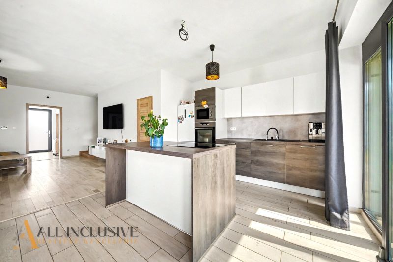 Küche in einem Einfamilienhaus mit Holzboden und weißen Schränken.