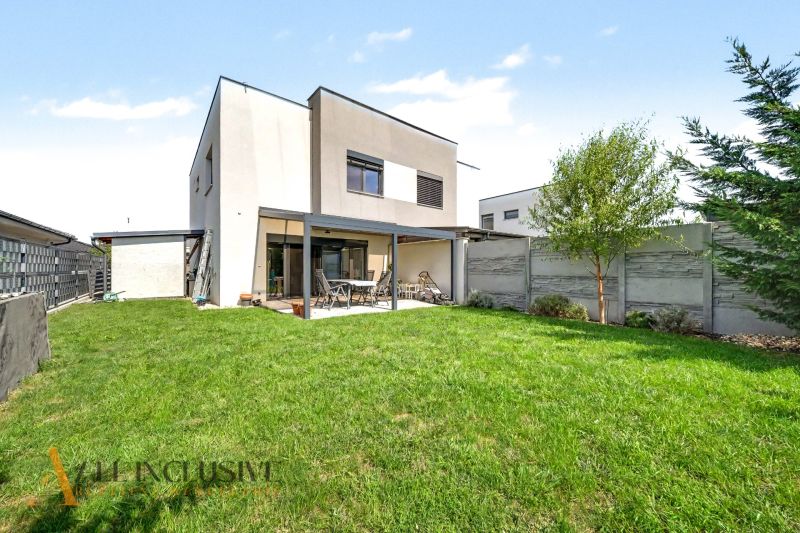 Ein Einfamilienhaus in Hrubá Borša mit Garten und Terrasse, umgeben von einer Hecke.