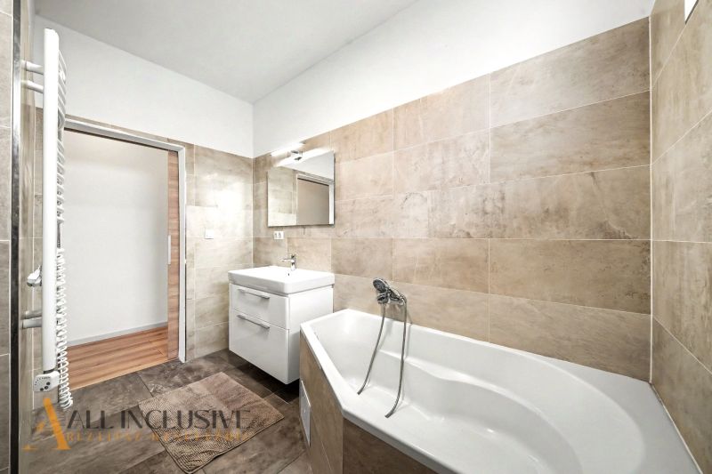 Badezimmer mit Badewanne und Waschbecken in einem Einfamilienhaus mit Fliesen in Beigetönen.