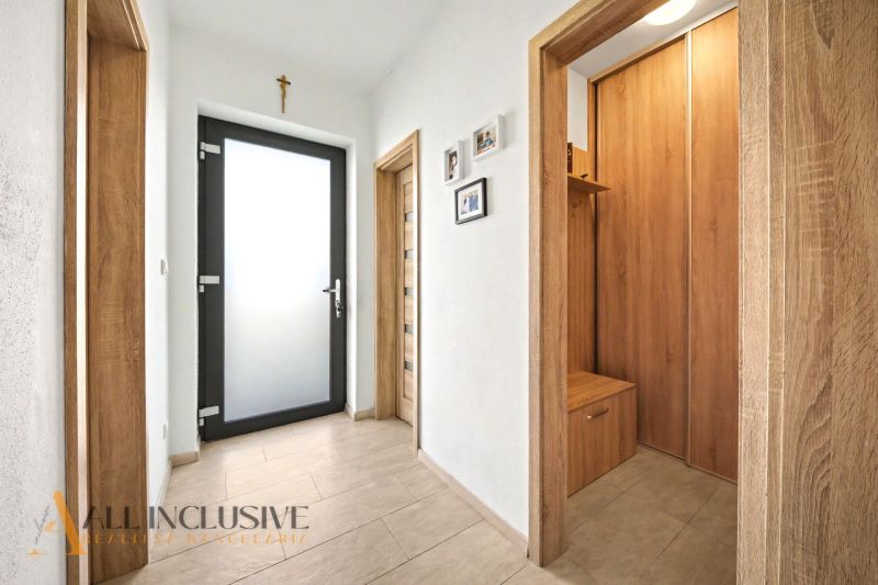 Der Flur in einem Einfamilienhaus mit Holzelementen und Fotos an der Wand.