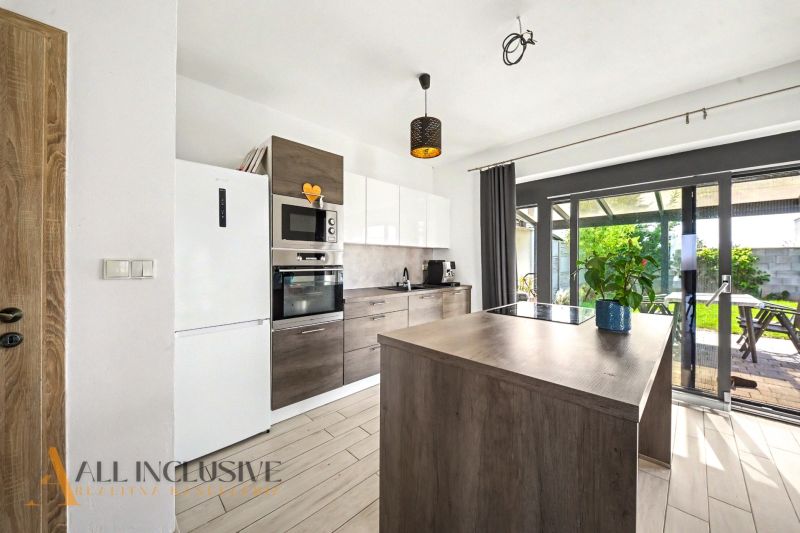 Eine Küche in einem Einfamilienhaus mit einem Holzboden und Glastüren zur Terrasse.