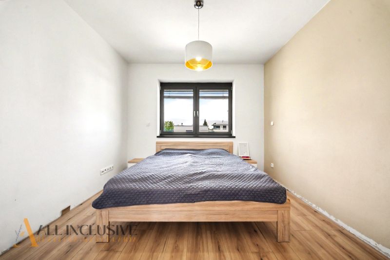 Helles Schlafzimmer mit Holzbett und Holzboden in einem Einfamilienhaus.