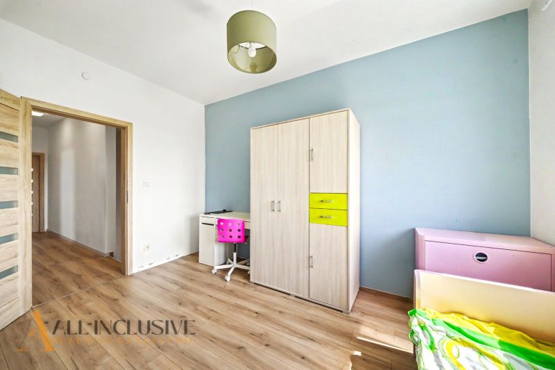 Ein Zimmer in einem Einfamilienhaus mit einem Boden in Holzoptik, Möbeln und farblichen Details.
