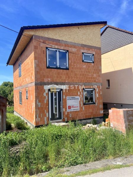 Unvollendetes Einfamilienhaus in Cerová mit sichtbaren Ziegelwänden und Kunststofffenstern.