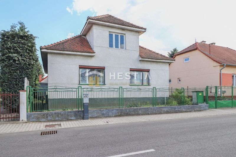 Ein Einfamilienhaus in Borský Mikuláš mit einem Dach aus roten Ziegeln und einem grünen Zaun.