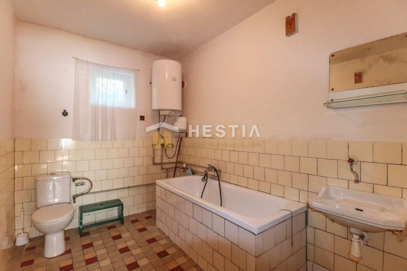 Badezimmer mit gefliester Badewanne und Boiler in einem Einfamilienhaus.