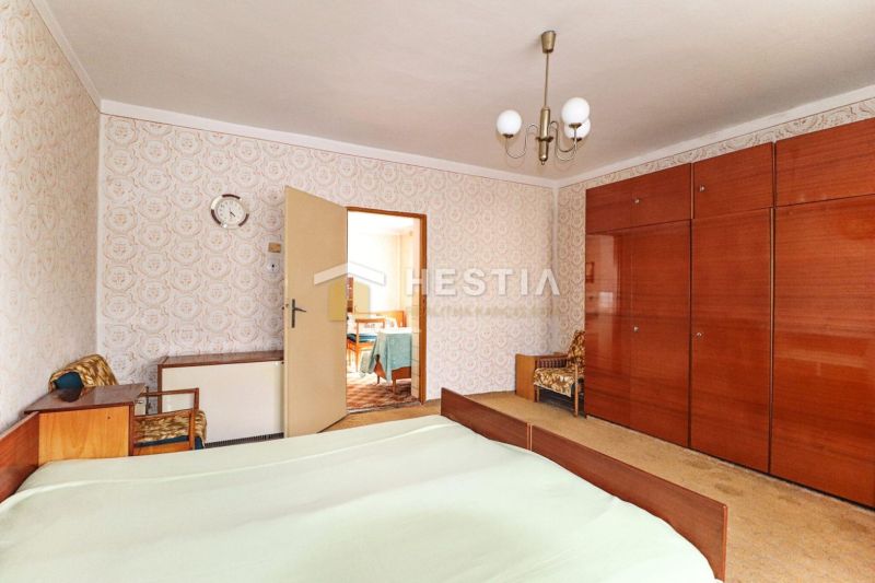 Schlafzimmer in einem Einfamilienhaus mit Retro-Möbeln und gemusterten Tapeten an der Wand.