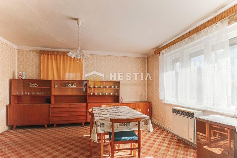 Innenraum eines Einfamilienhauses mit Esstisch, älteren Möbeln und Teppich.