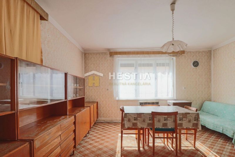 Esszimmer in einem Einfamilienhaus mit Retro-Möbeln und Teppich, dominiert von einem hellen Fenster.