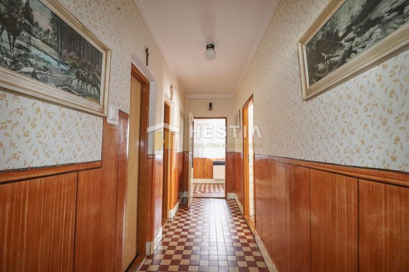 Ein Flur in einem Einfamilienhaus mit Oberflächen in Holzdekor und gemustertem Boden.