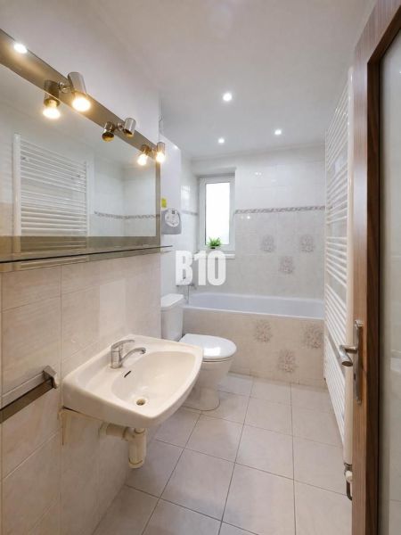 Badezimmer mit Badewanne, Waschbecken und Fenster in einer 3-Zimmer-Wohnung.